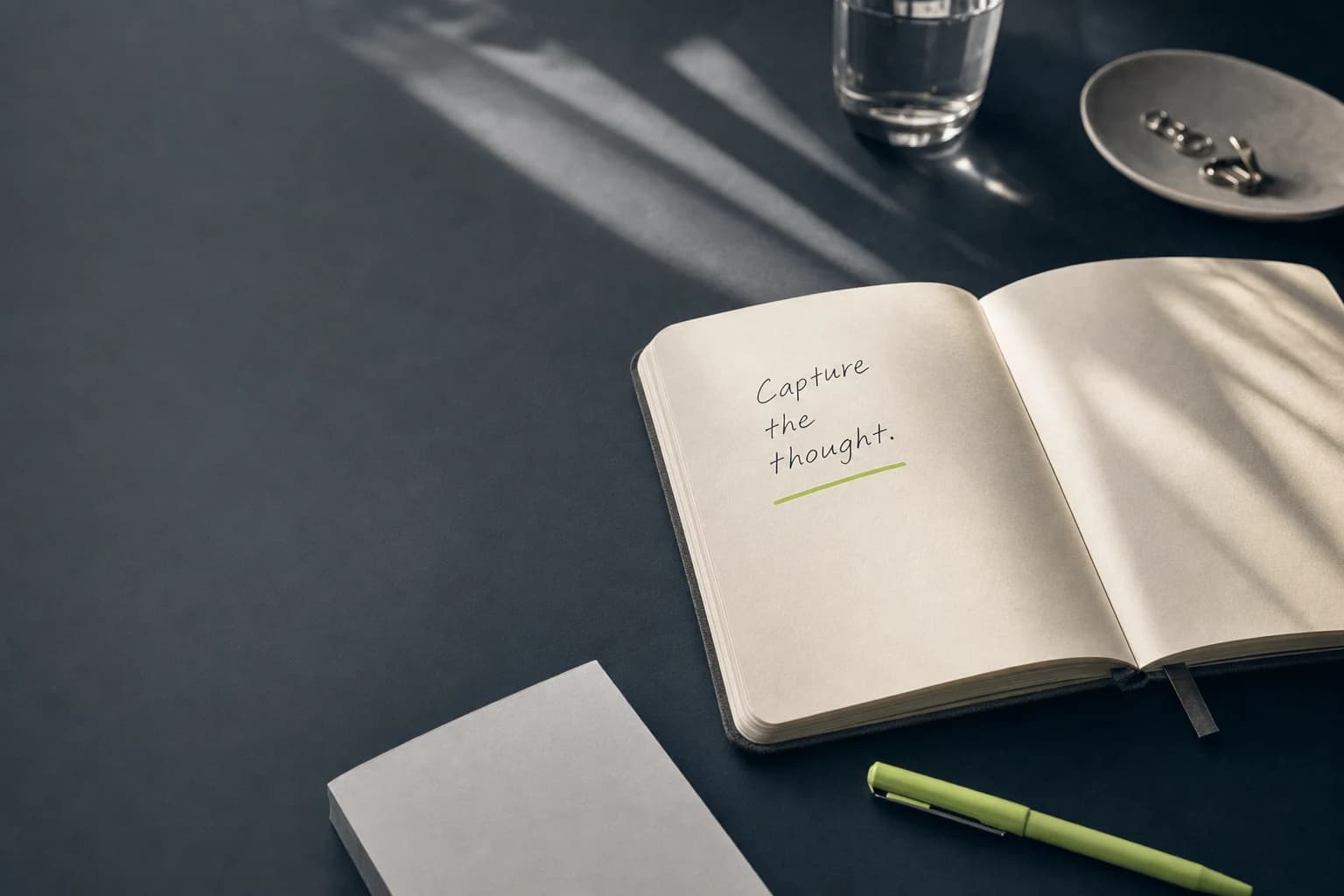 An open notebook on a dark desk with a single lime underline